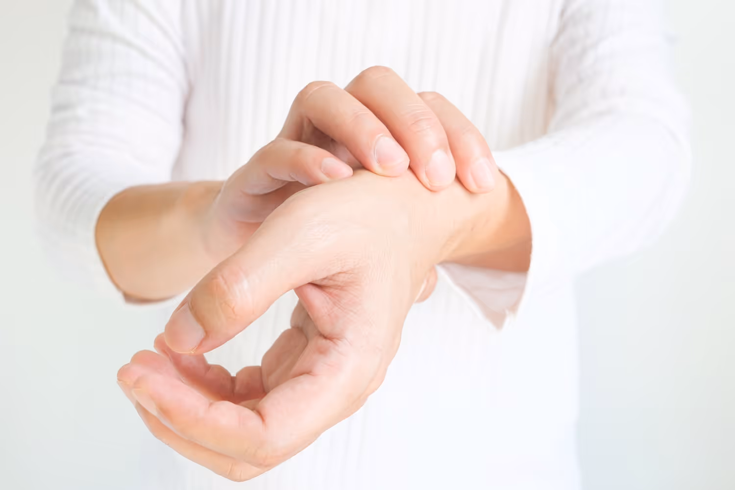 Nærbilde av en person som holder seg til tommelen og innsiden av hånden på grunn av smerter.
