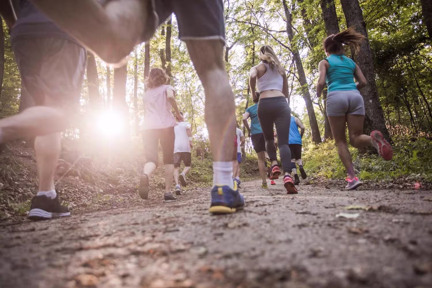 Gruppe løpere på skogsti sett fra bakkenivå. Gjentatt løpsbelastning er en vanlig årsak til akillestendinopati, særlig ved rask økning i treningsvolum eller intensitet.