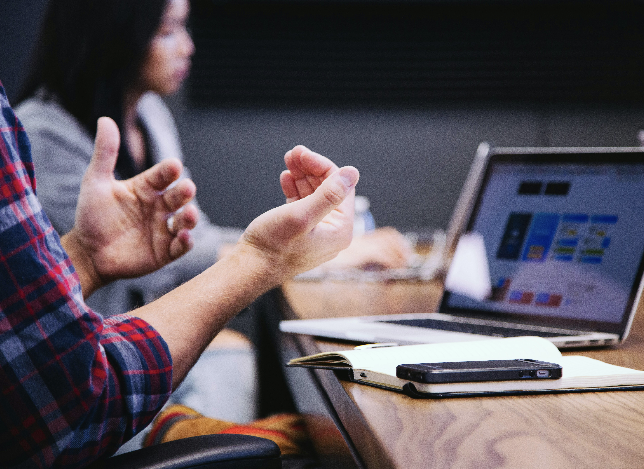 Close up of a designers hands gesticulating in conversation in front of an open laptop