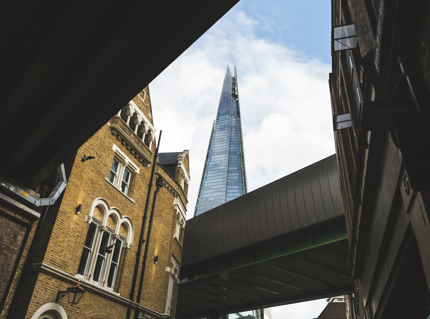 Photo of the Shard building in London Bridge from Borough Market looking up between buildings.