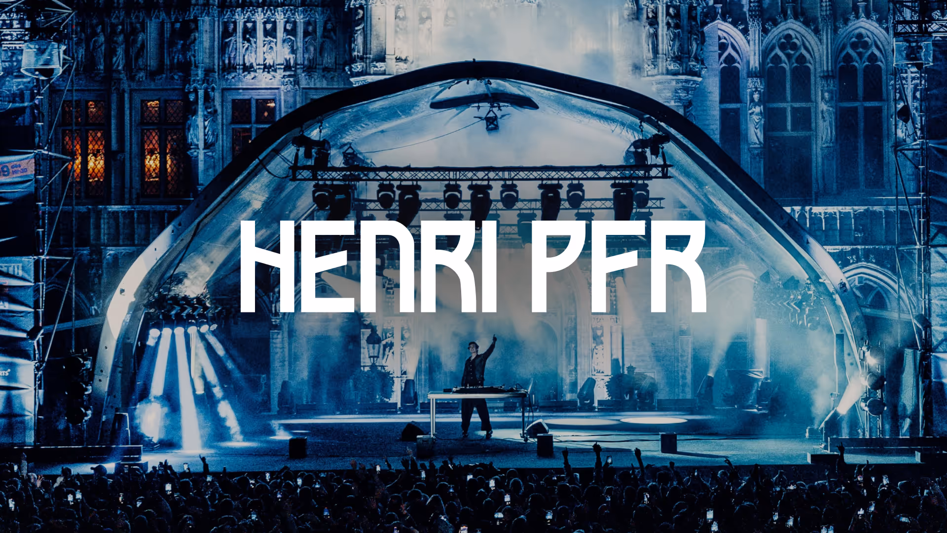 Henri PFR performing on stage at night with blue lighting and a large crowd in front.