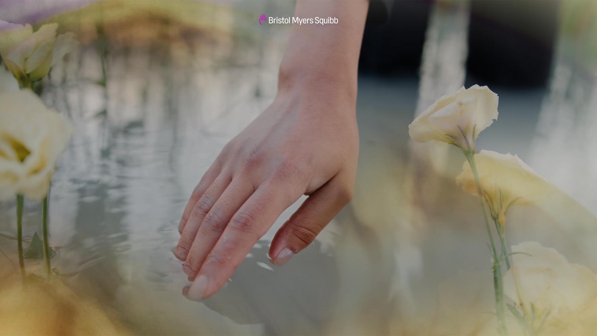 A hand is shown dipping its fingers into water with semi-transparent photos of flowers surrounding it.