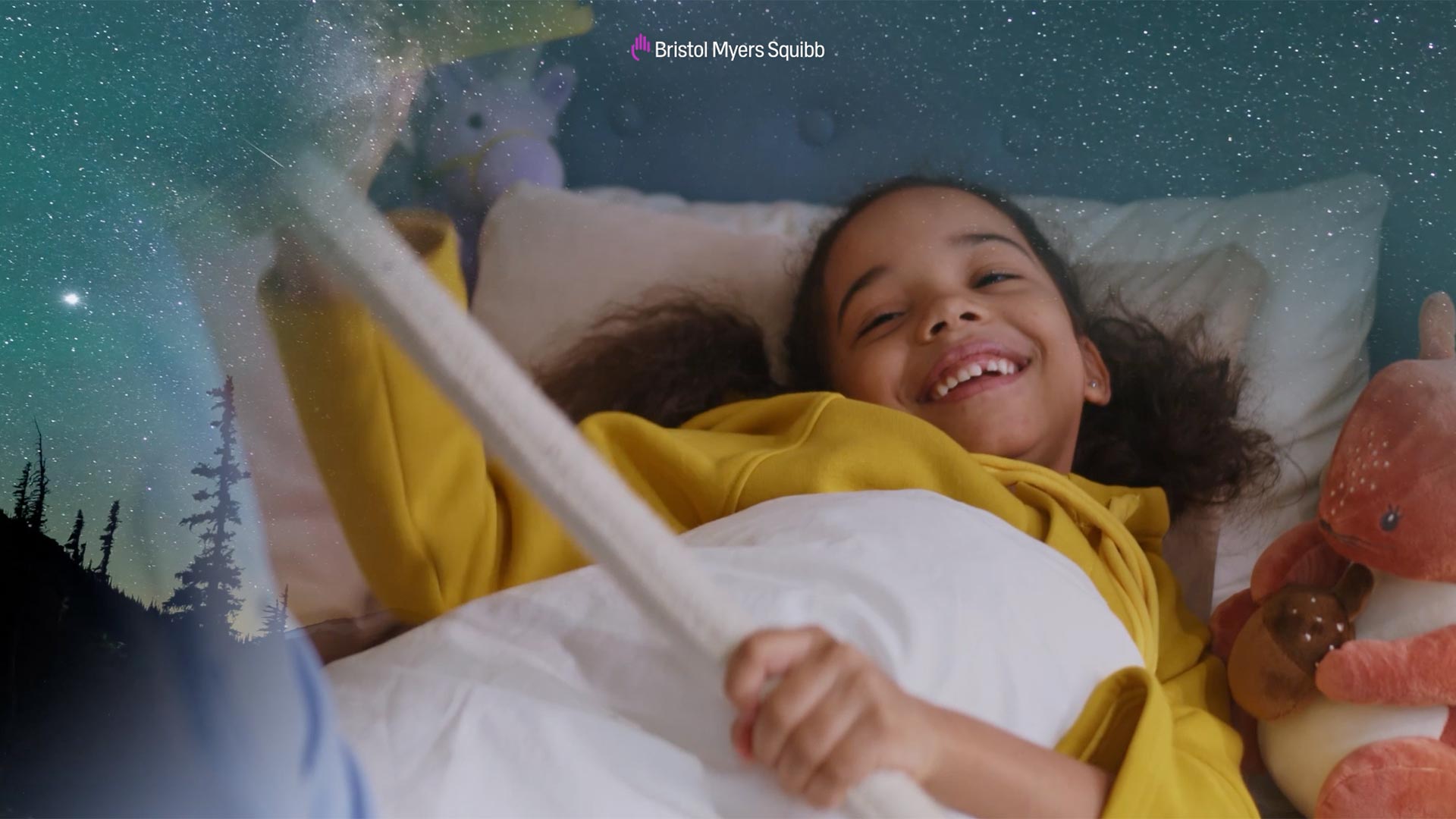 A young girl enjoys story time in bed surrounded by stuffed animals as forest imagery approaches the corner of the frame.
