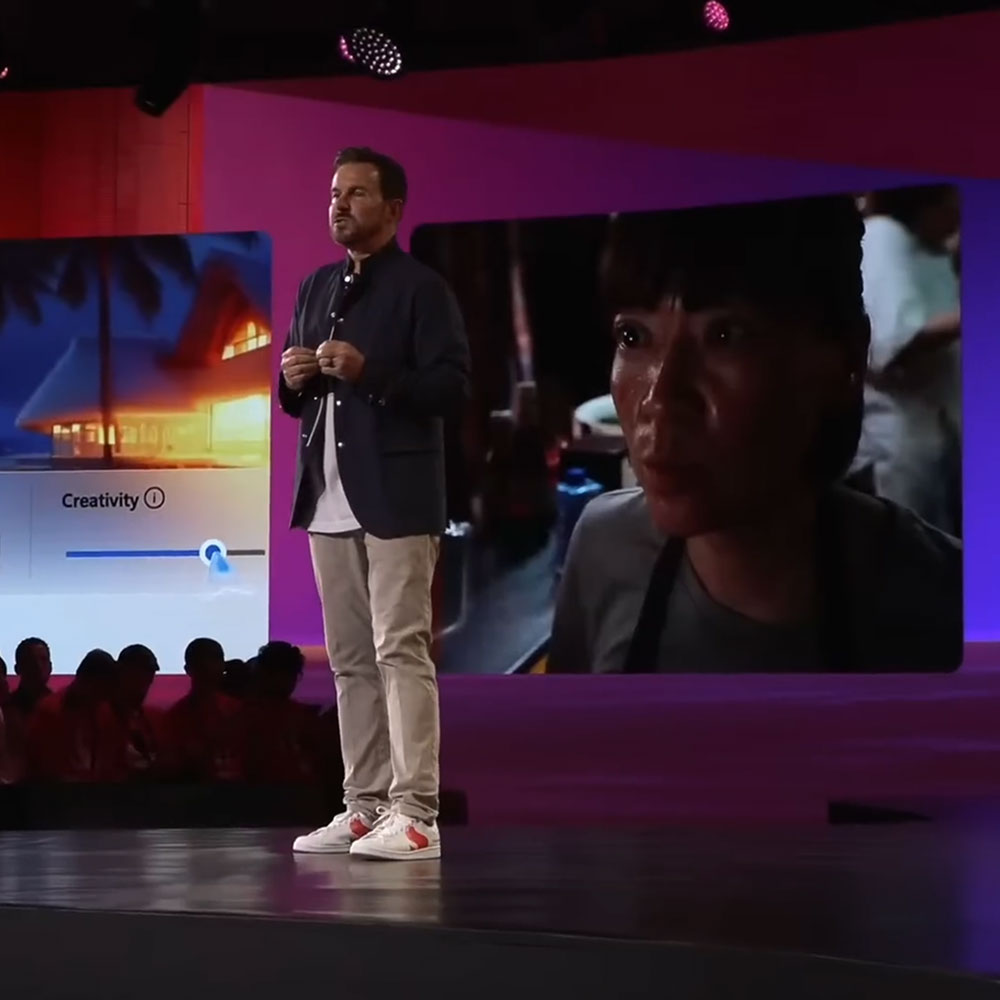 A man is onstage at Snapdragon Summit in Maui, Hawaii. The screen behind him shows photo editing tools powered by Snapdragon.