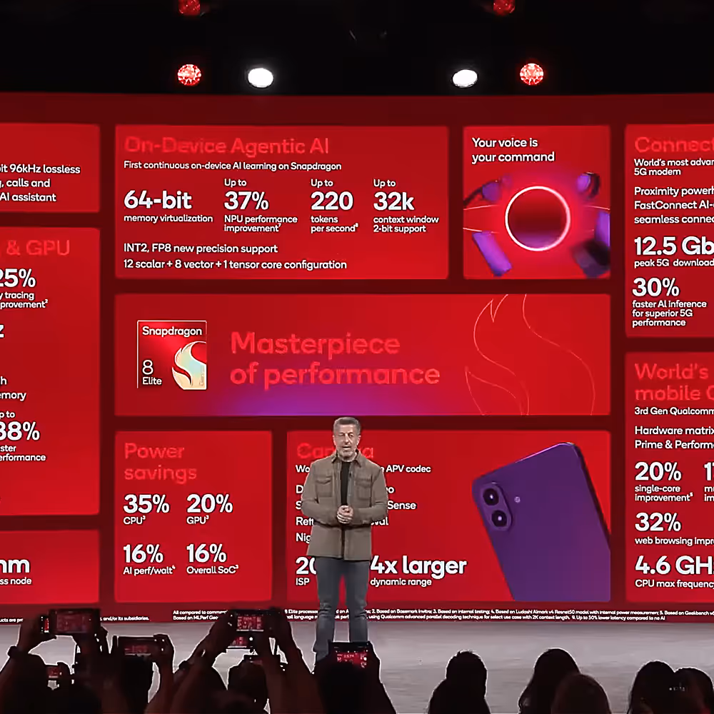 The big screen at Snapdragon Summit shows a grid of graphics listing statistics for on-device agentic AI and more.