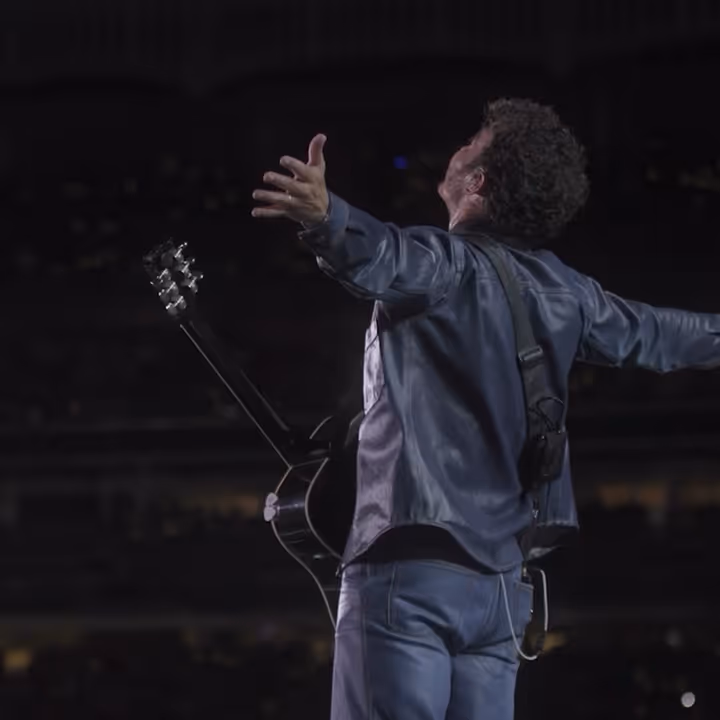 Kevin Jonas is shown from behind with his guitar as he performs on tour with The Jonas Brothers.