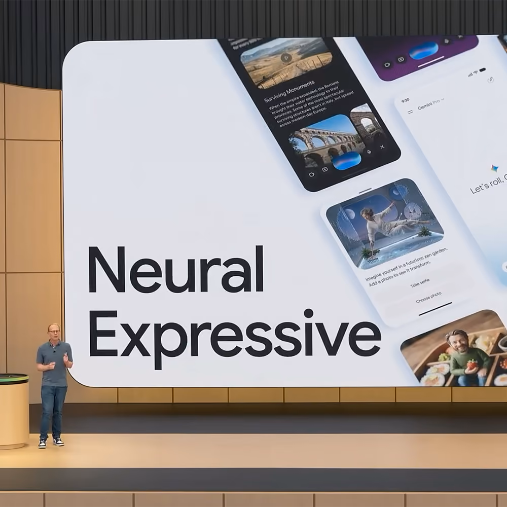 A speaker on stage next to a large display reading “Neural Expressive” alongside mobile app interface mockups.