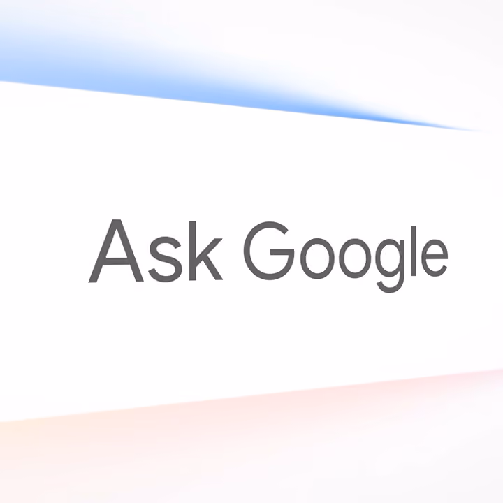 An angled close-up of a bright white presentation screen displaying the grey text “Ask Google.”