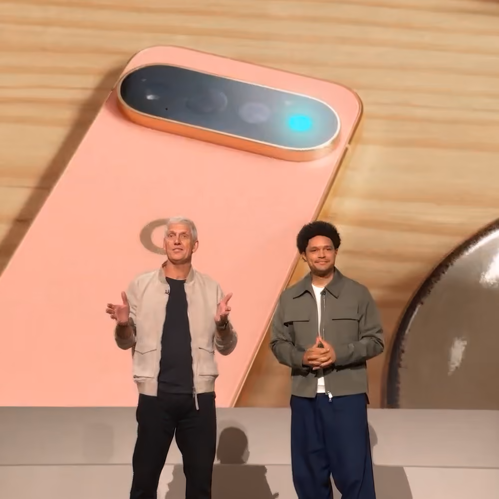 Rick Osterloh and Trevor Noah on stage presenting in front of an image of a canyon-colored Pixel phone.