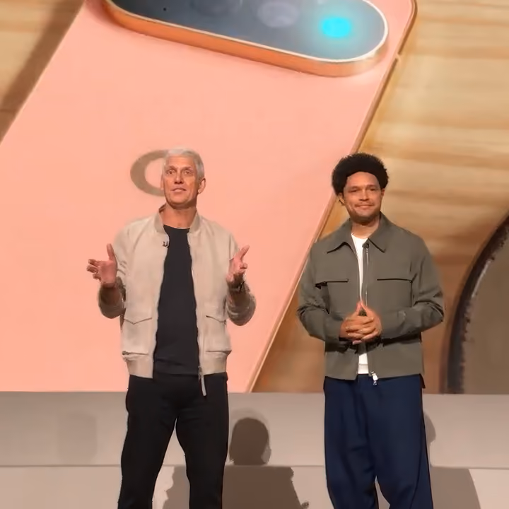 Rick Osterloh and Trevor Noah on stage presenting in front of an image of a canyon-colored Pixel phone.