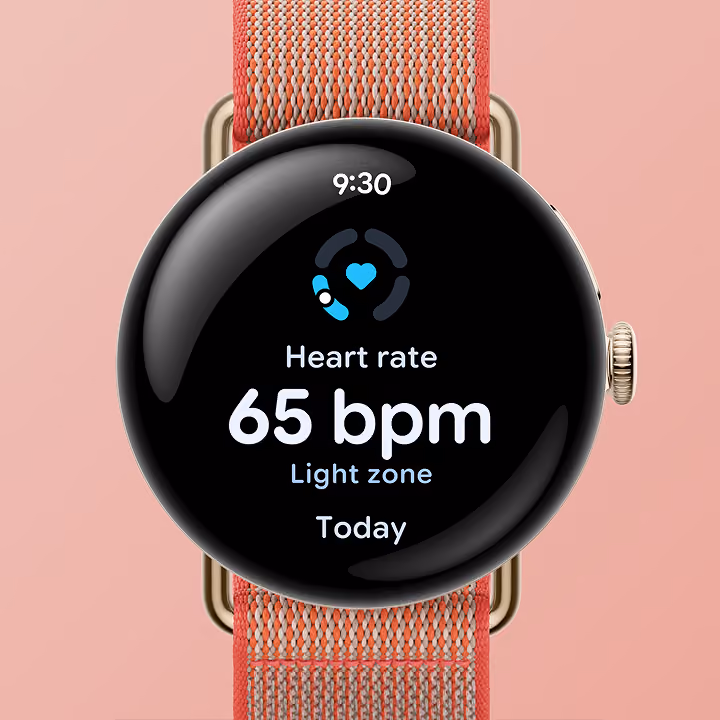 Google Pixel Watch with a coral woven band displaying a heart rate reading of 65 bpm.
