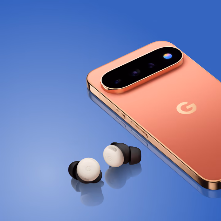 A canyon-colored Google Pixel smartphone resting beside a pair of white and black Pixel Buds on a glossy blue surface.