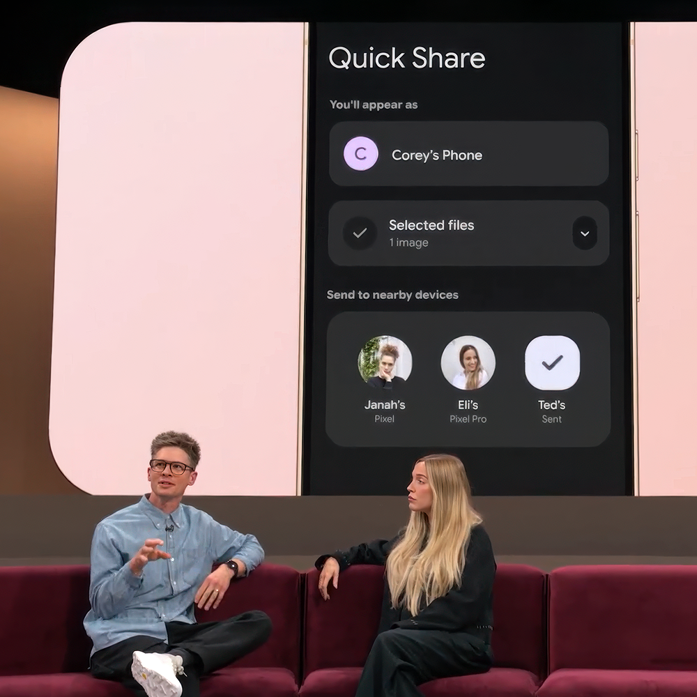 Two presenters sit on a couch in front of a screen demonstrating the Quick Share feature on a Pixel phone.