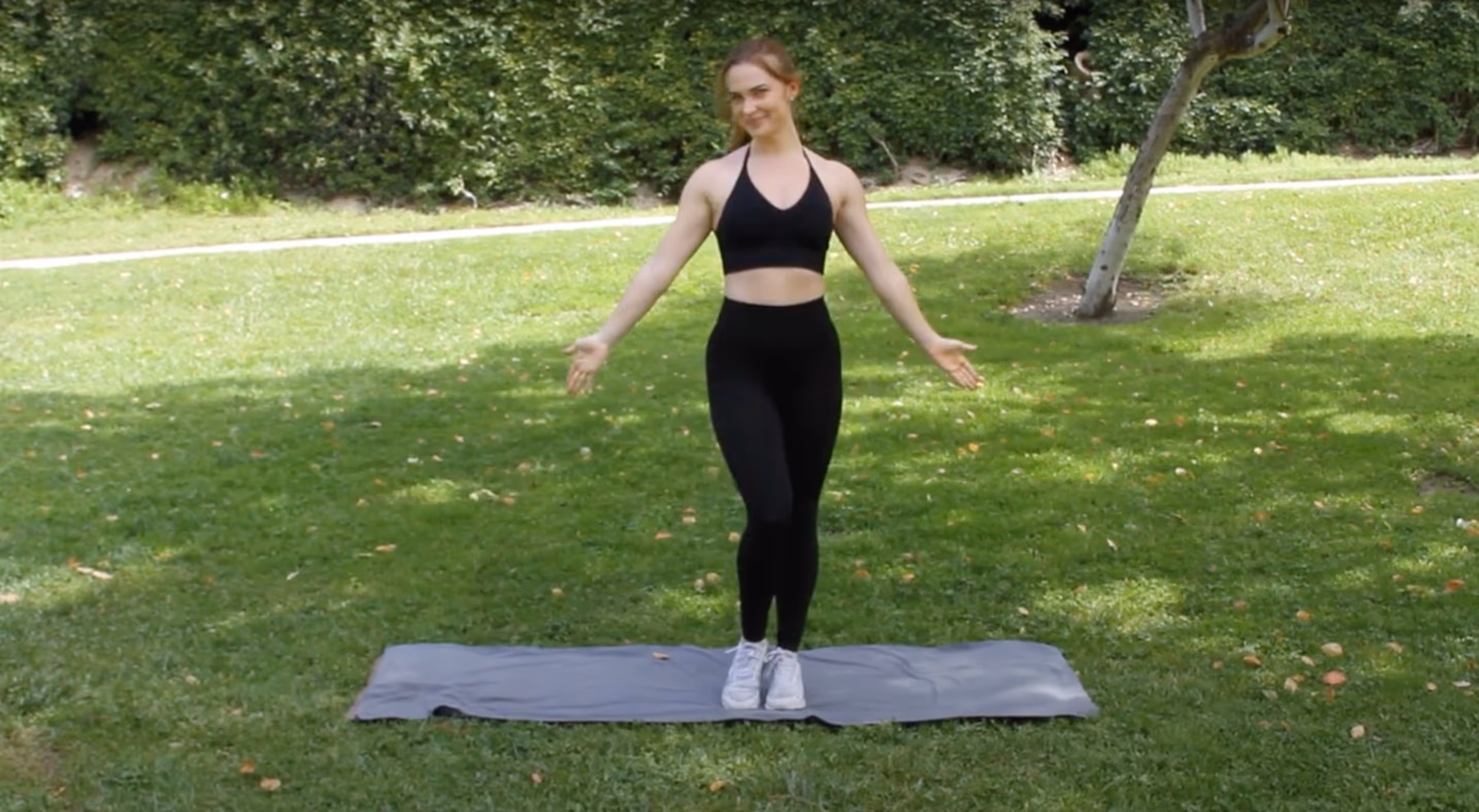 Shelby Barry standing on a yoga mat on the grass