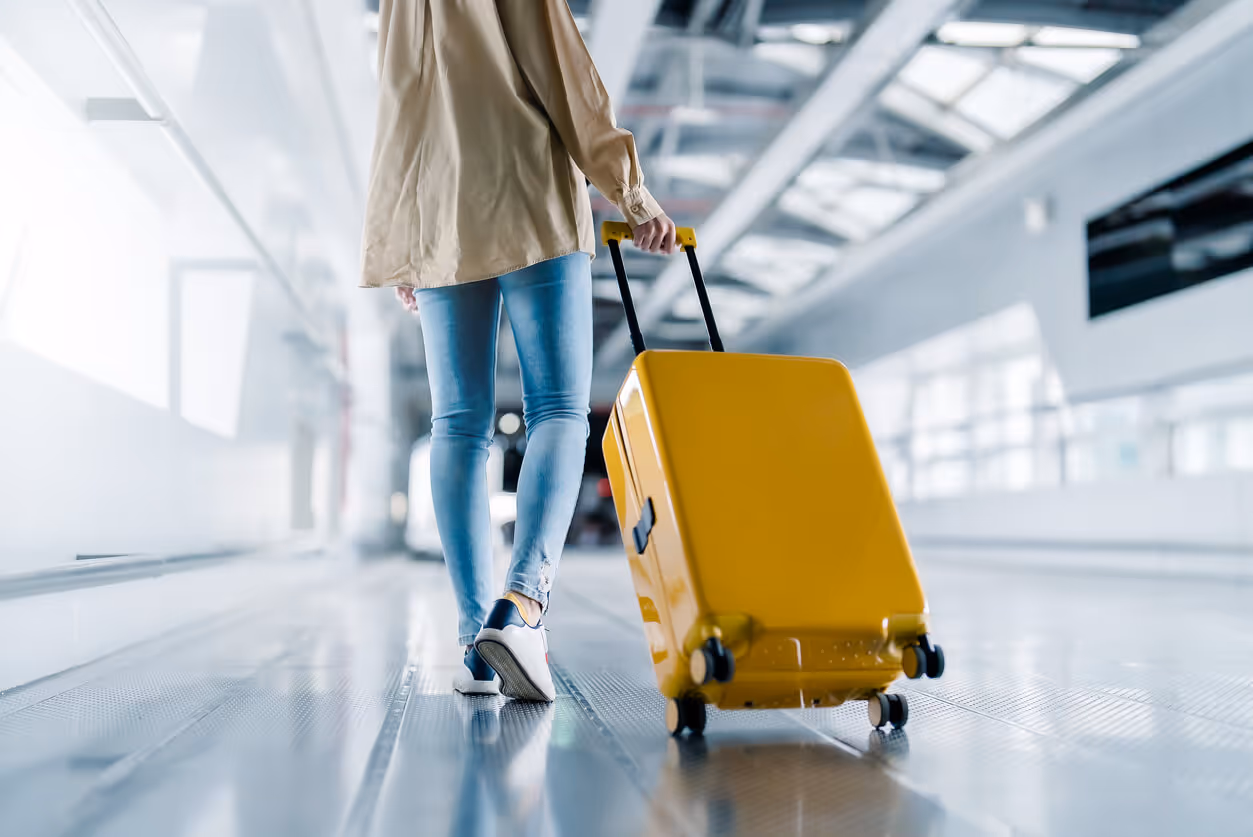 Person rolling a yellow suitcase in the airport