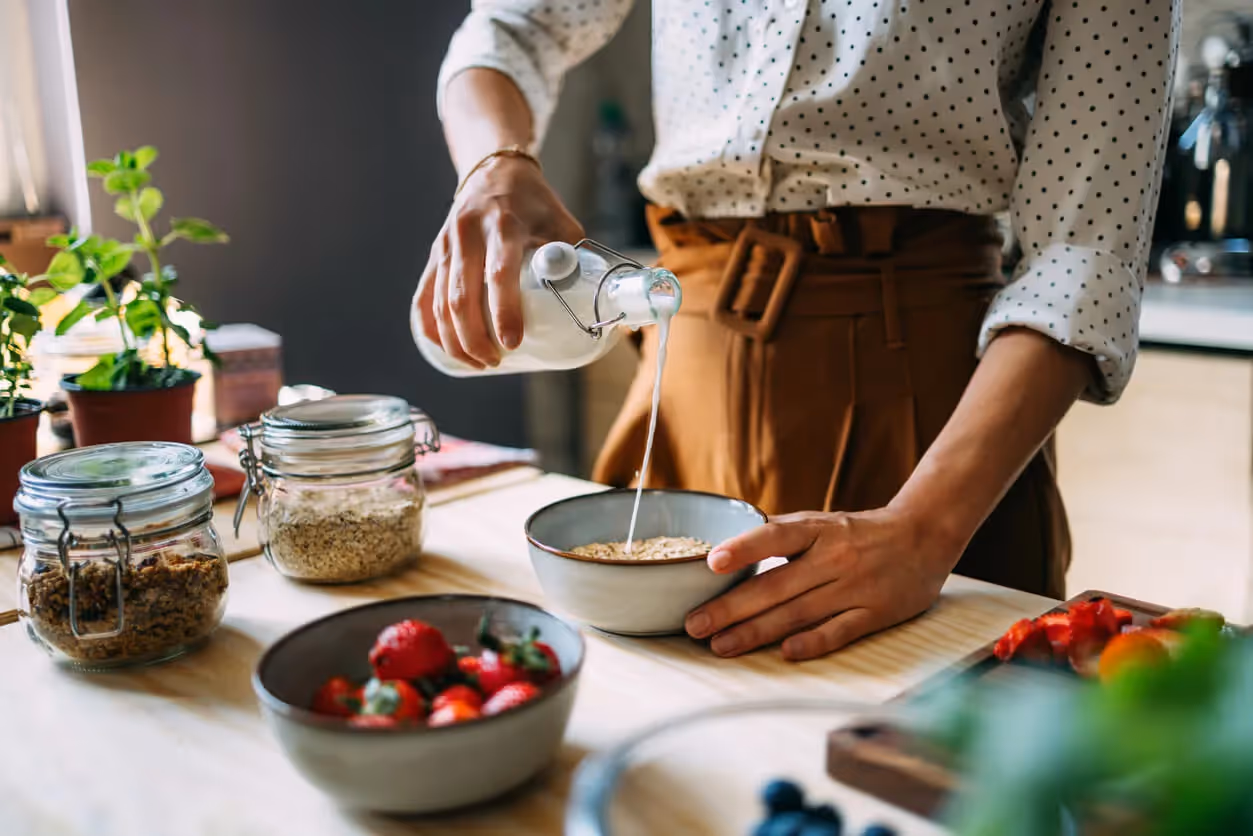 Woman pouring milk into oatmeal