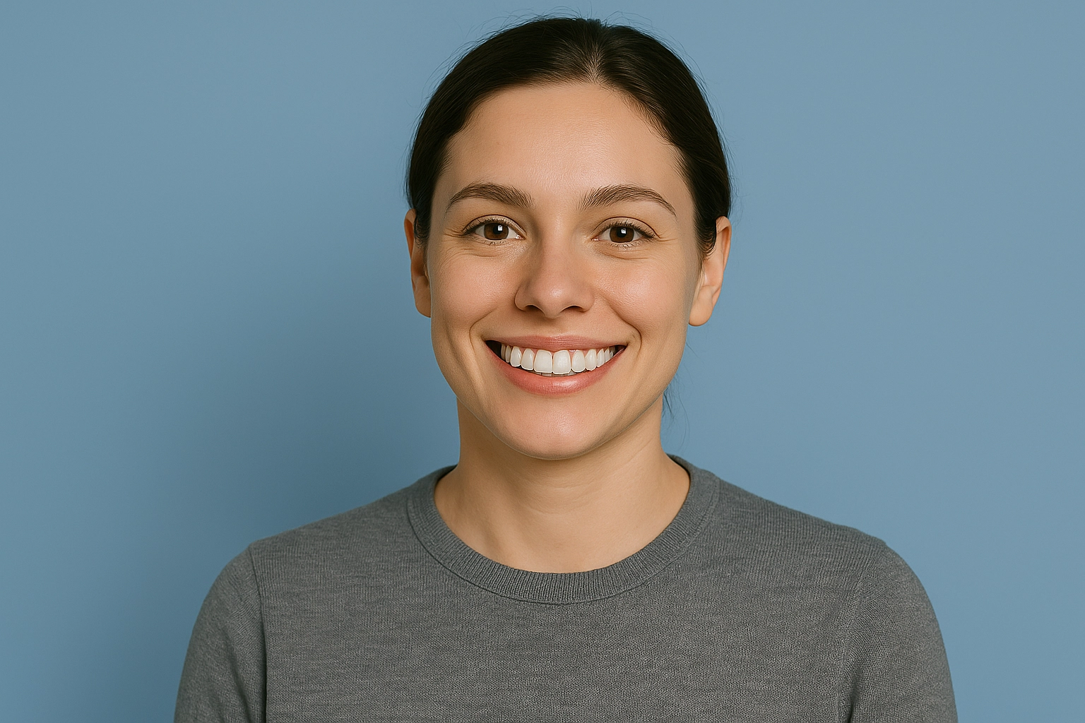horizontal photorealistic portrait of smiling woman with white teeth wearing gray shirt against light blue background