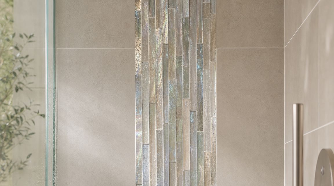 A vertical accent strip of shimmering iridescent glass tiles between large beige wall tiles in a shower.