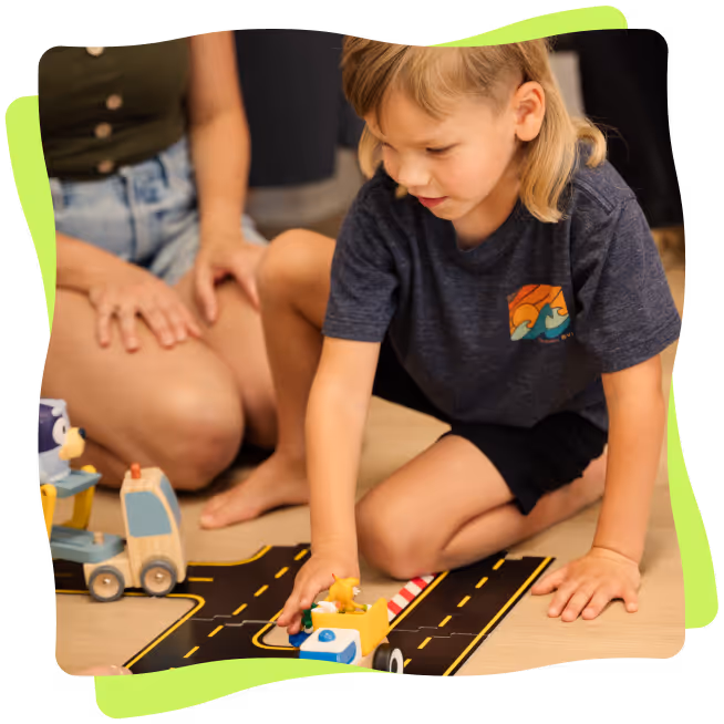 Mother and son playing on ground with toy cars and street