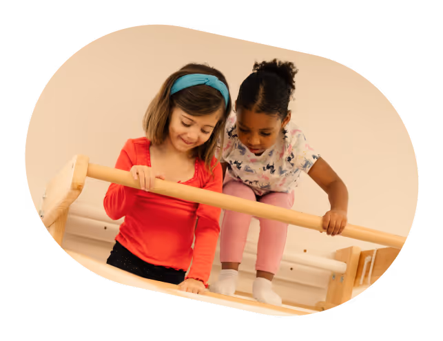 Two young girls playing on monkey bars