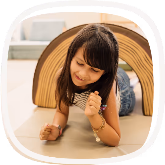 Young girl crawling through foam tunnel on floor.