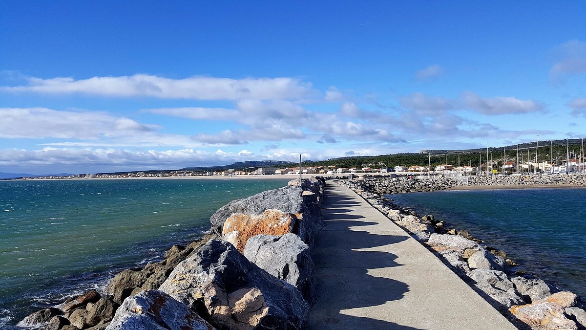 Plage de sable fin avec parasols et cabine rayée à Narbonne-Plage en été — location saisonnière Narbonne Méditerranée