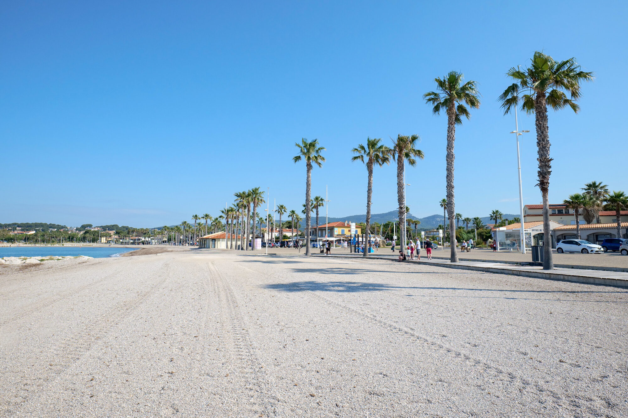 Plage de sable et promenade bordée de palmiers à Six-Fours-les-Plages, station balnéaire du Var — location saisonnière Airbnb Six-Fours