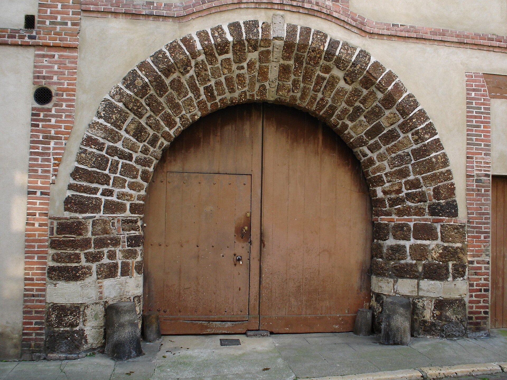 Porche ancien en pierre de grison et briques à L'Aigle — gestion locative Orne