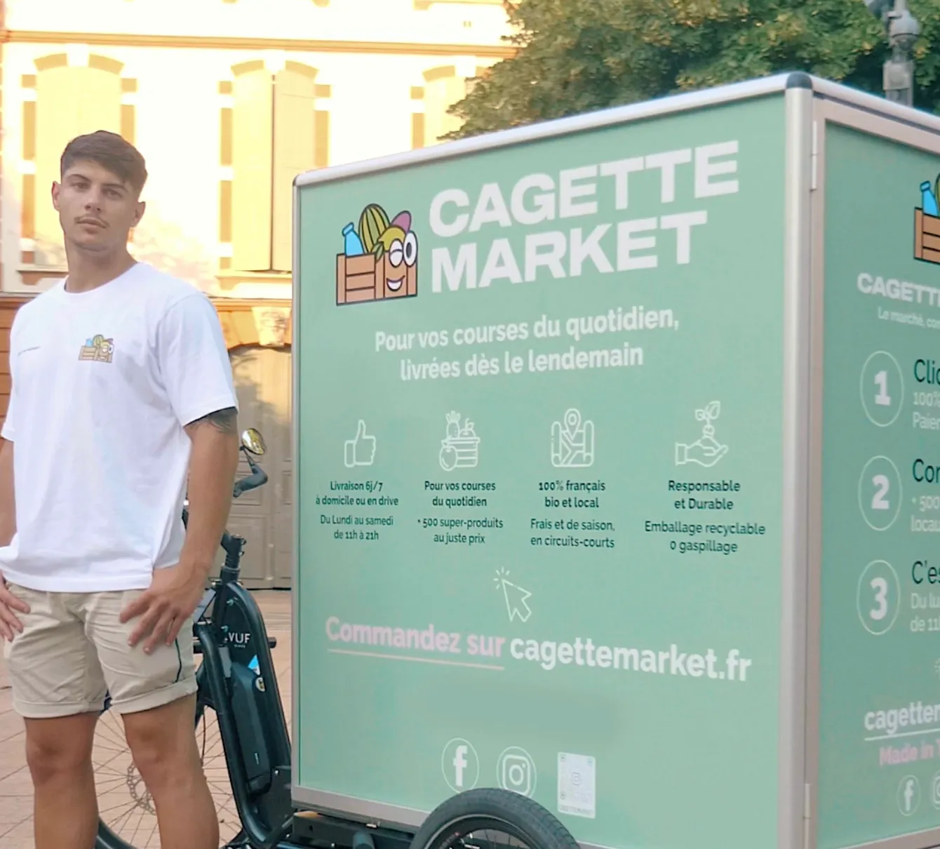 Young man standing next to a bicycle in front of a green Cagette Market advertising cart in the city.