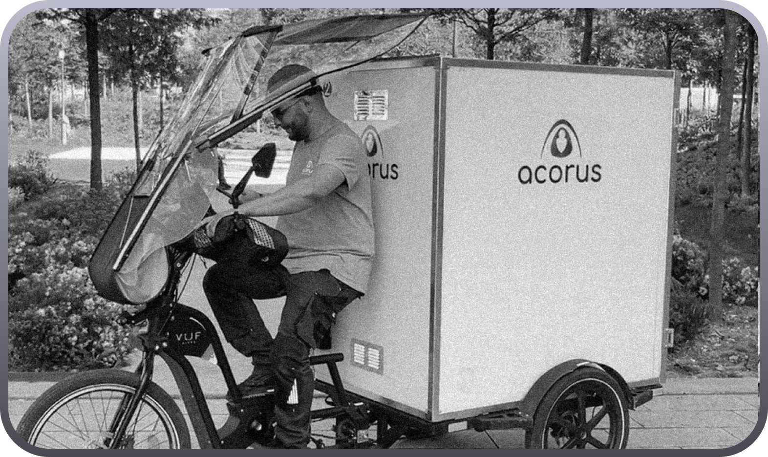 A man on an electric cargo bike with a large white box marked acorus.