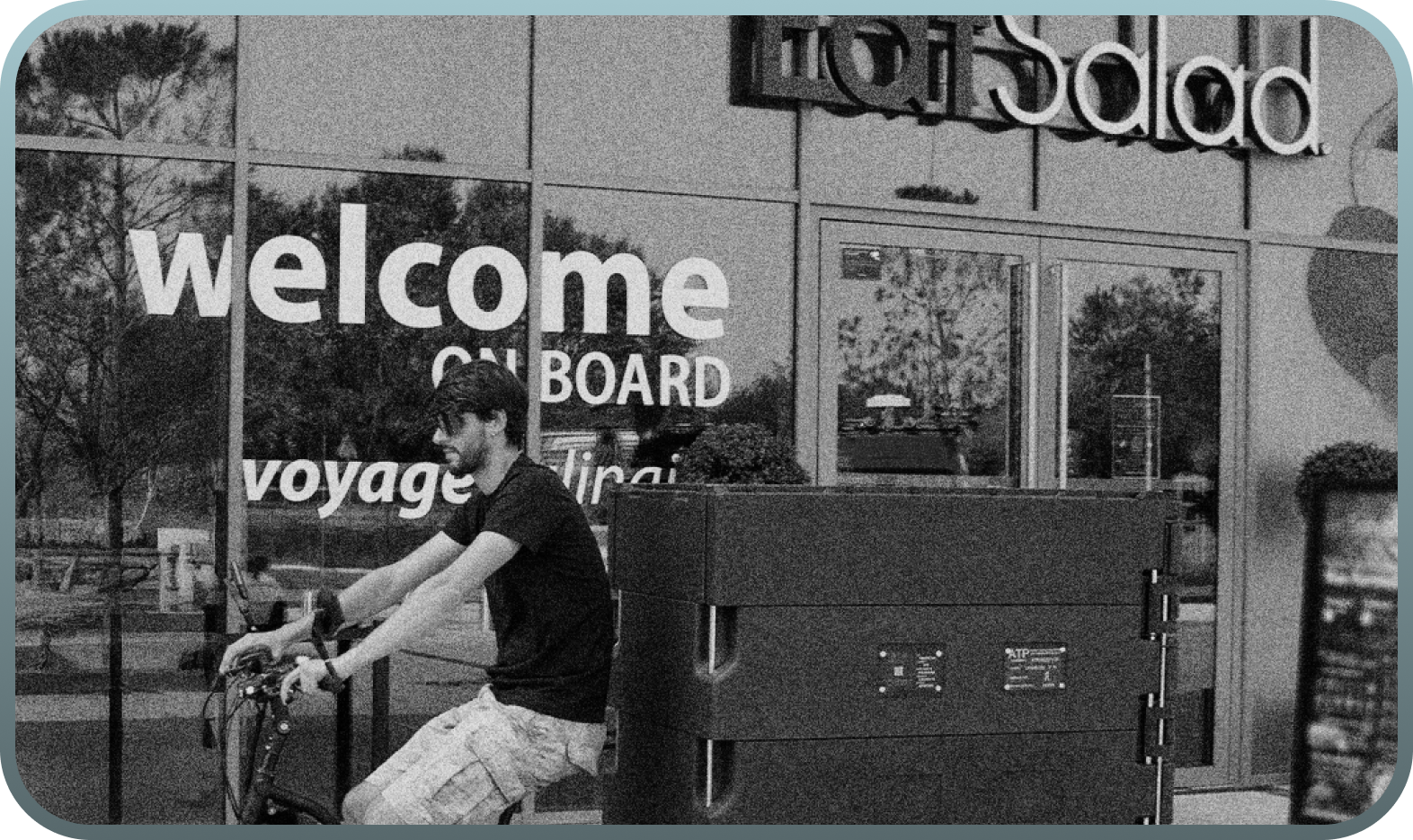 A man on a bike in front of a shop window with the text "welcome onboard".