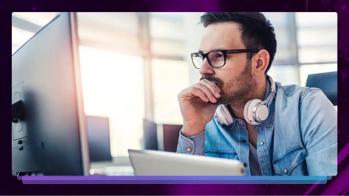 A man sits at a desk while working at a computer. 