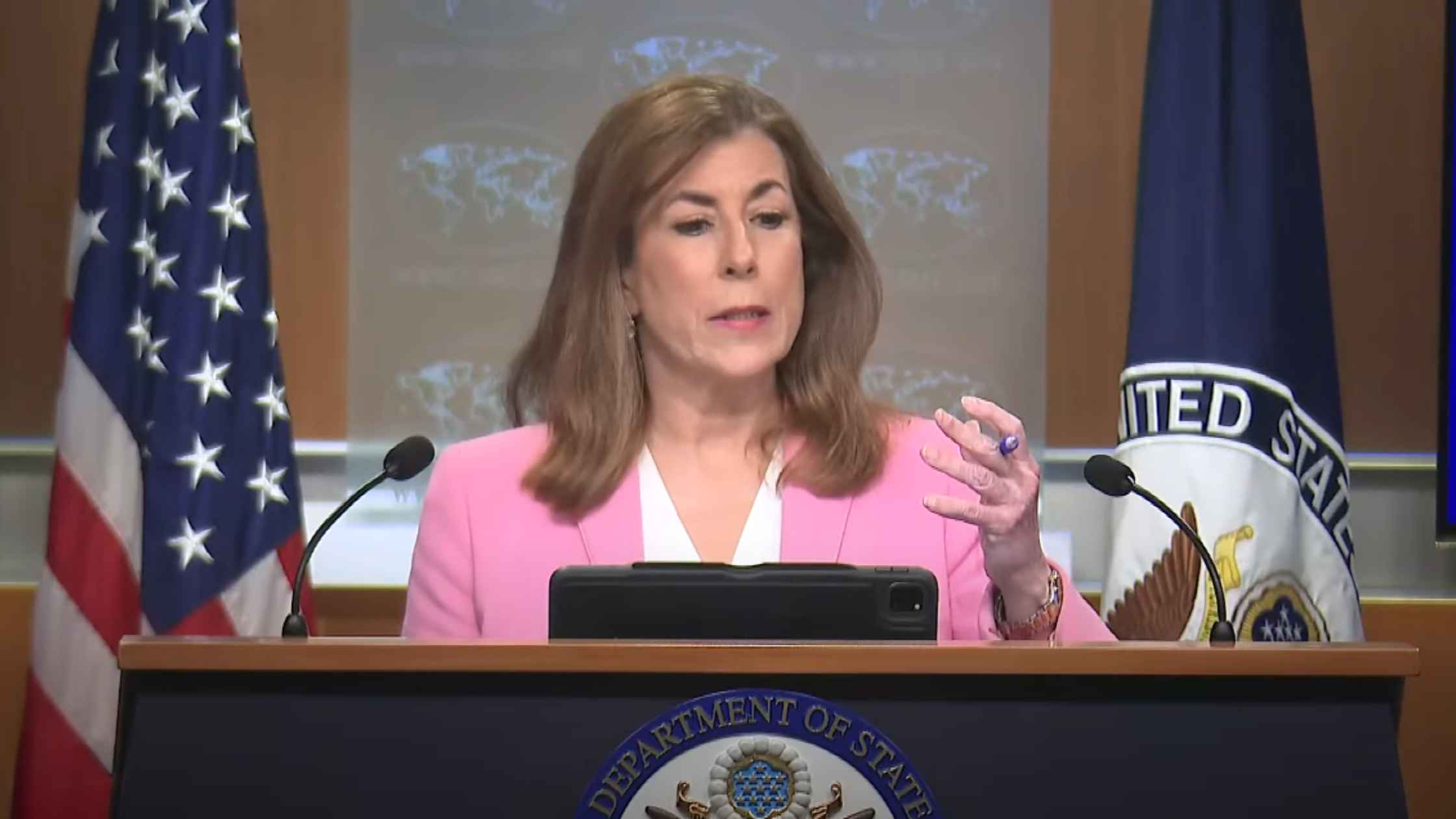 Tammy Bruce speaks and gestures to the press. 