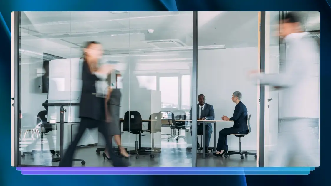 Legal professionals walking past and working in a modern conference room.
