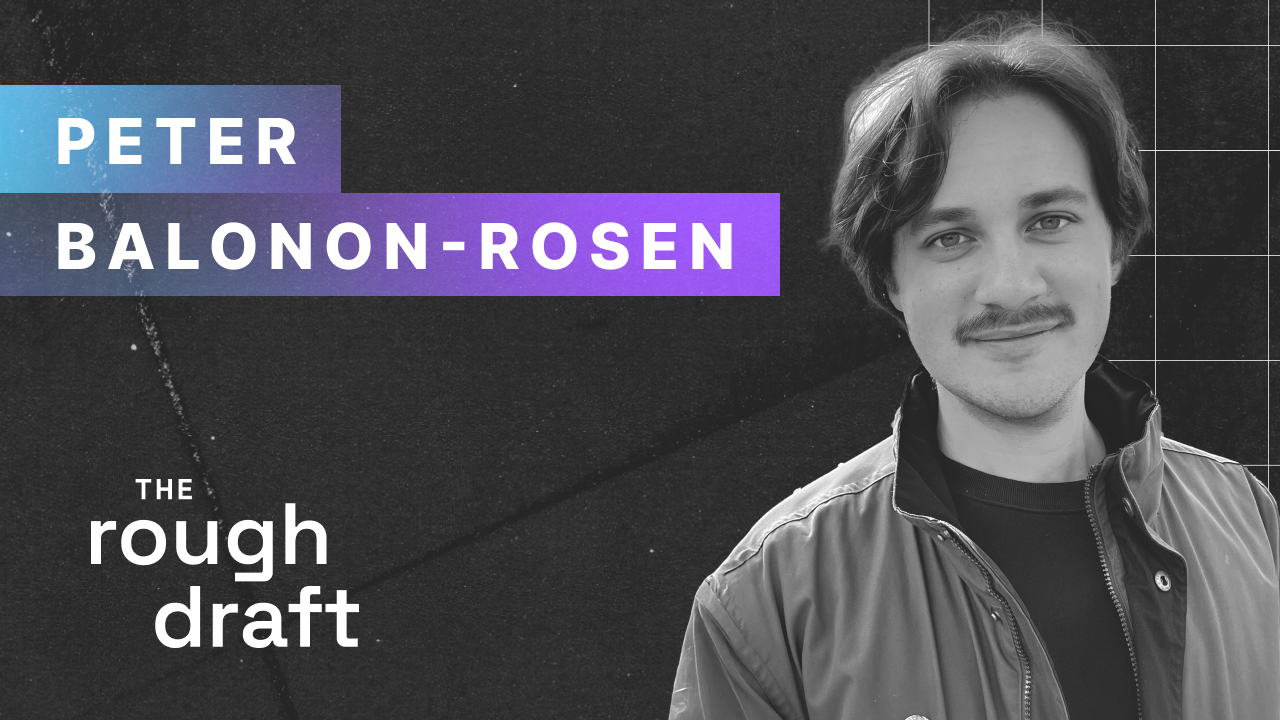 Professional headshot of a person smiling in blazer against a soft gray studio background