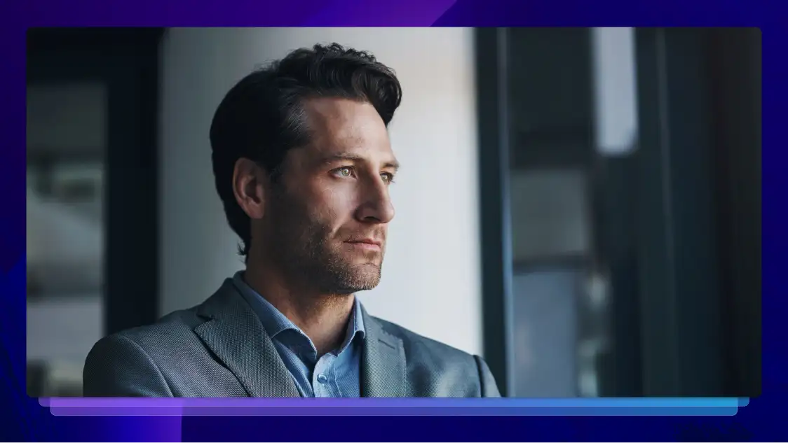 Professional man in a suit looking thoughtfully out of an office window.