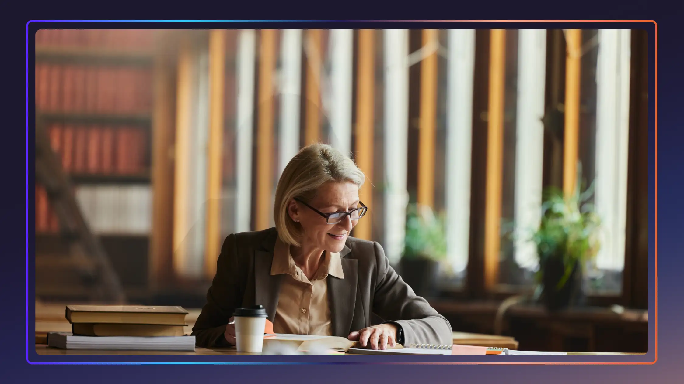 Professionally dressed woman in a library looking over her notebook next to a coffee and a stack of books.