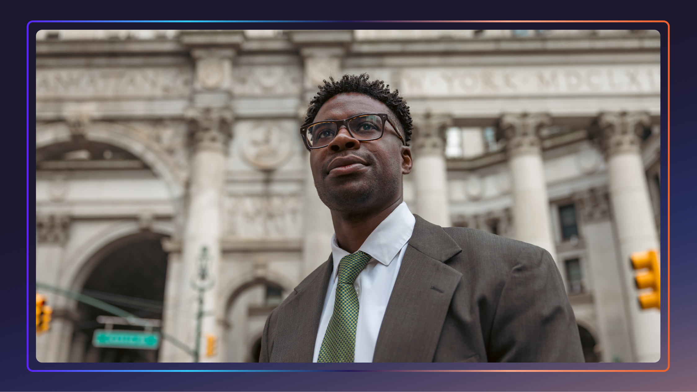 A young male lawyer stands in front of a New York building and looks off camera.