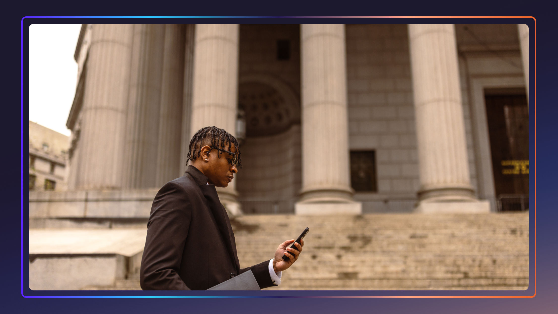 A young lawyer walks in front of a government building looking at his cell phone.