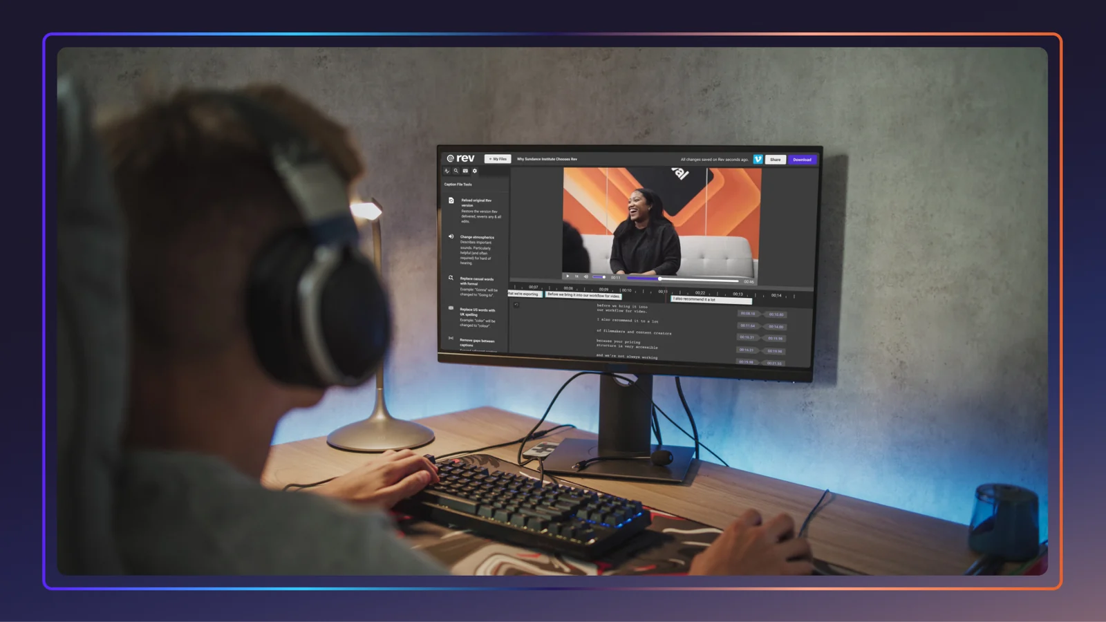 A man in headphones sits at a computer, editing captions on a video within the Rev platform.