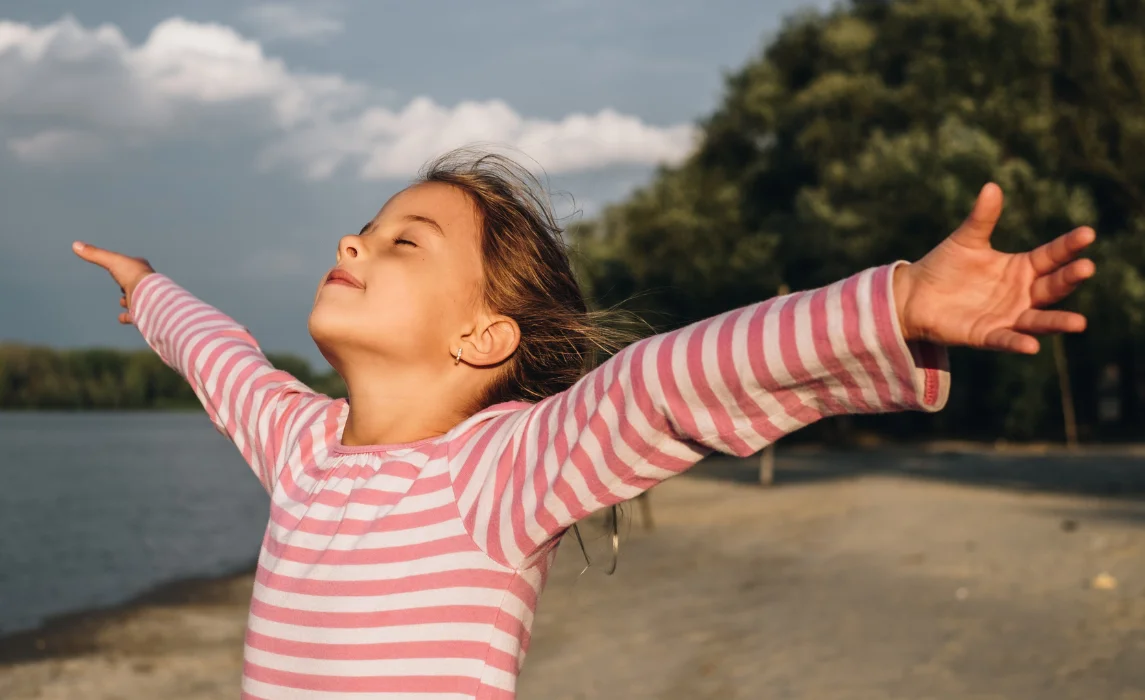 kid opening her arms wide hugging the wind