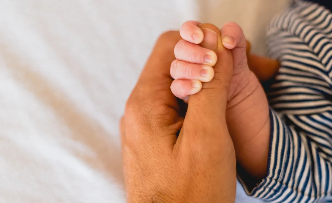 baby holding a thumb