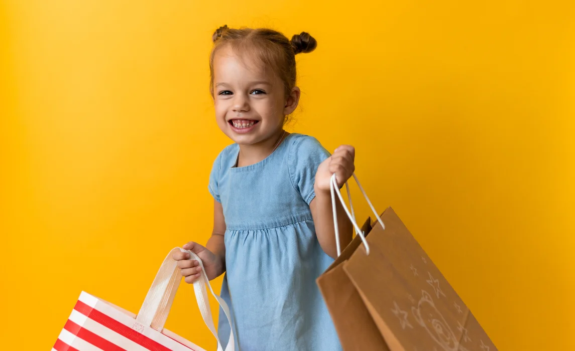 girl in yellow background holding shopping bags