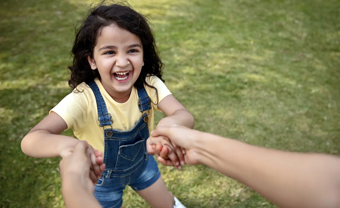 kid playing in the park with her parent