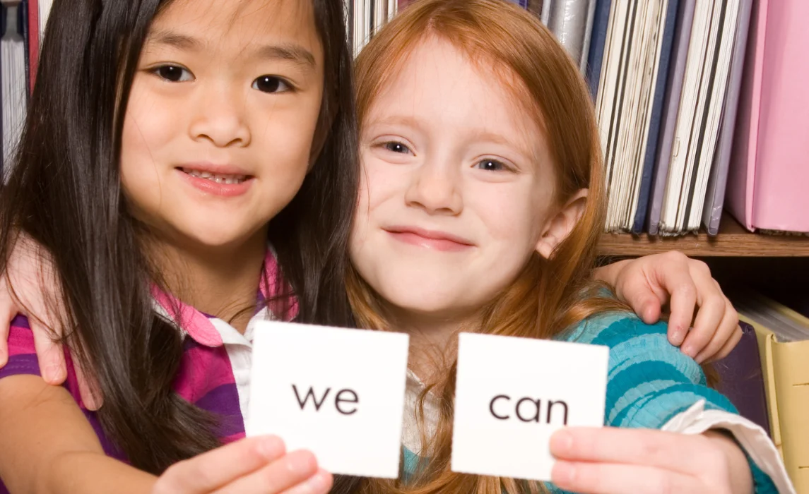 two kids showing a card with written word in it