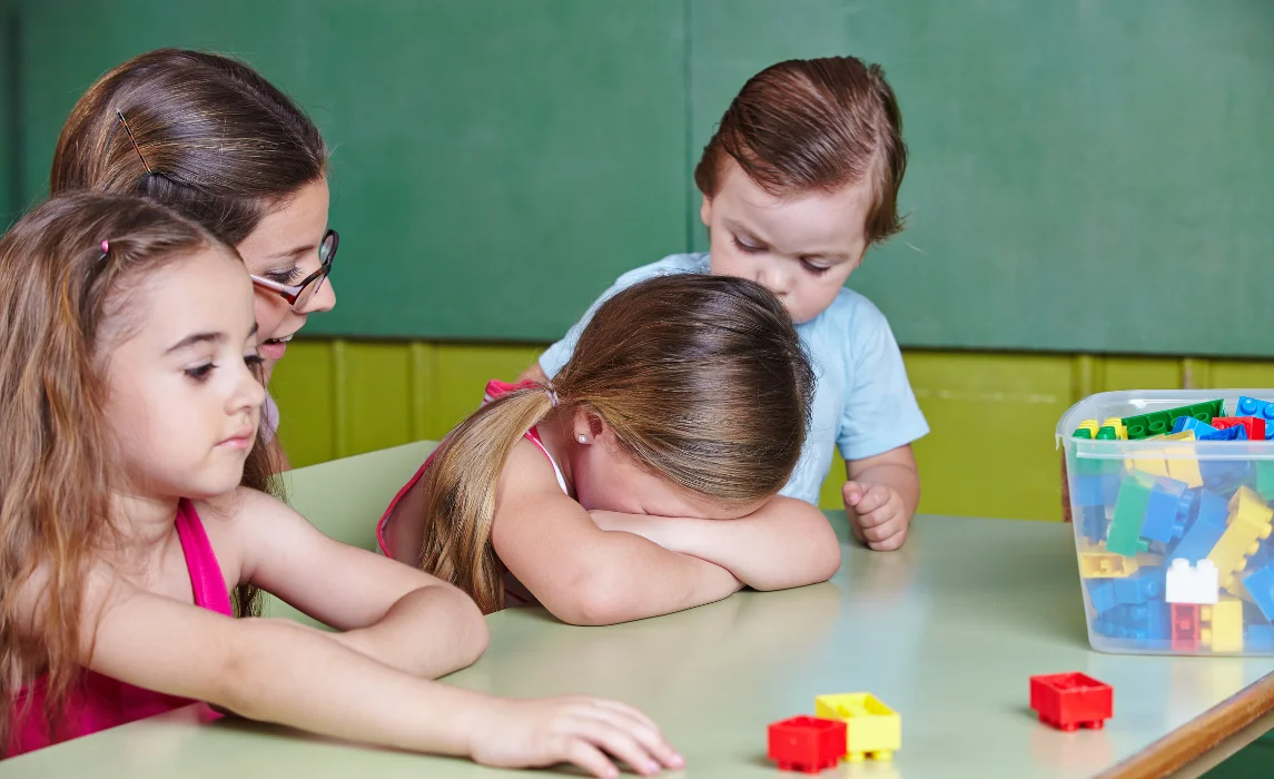 kid crying in the classroom while being comforted by her classmates