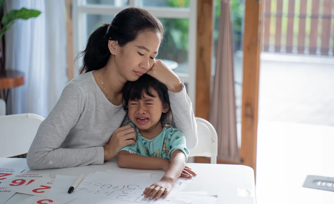 kid crying while being hugged by her mother