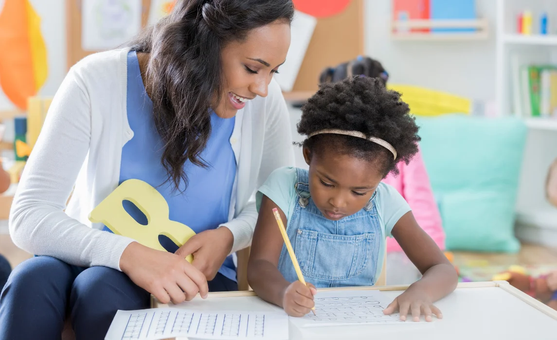teacher teaching a girl to write