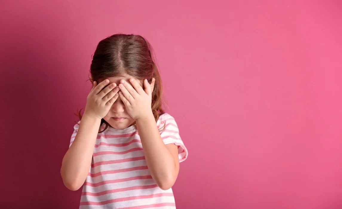 kid closing her eyes in pink background
