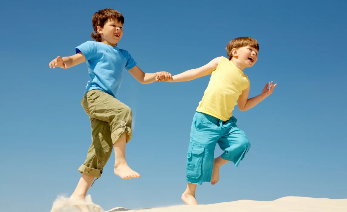 two kids running on the sand